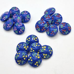 Puede incluir: Un conjunto de botones azules con diseños florales tallados. Los botones presentan detalles rosas, rojos y amarillos, que añaden color a las intrincadas tallas. Estos botones decorativos son ideales para proyectos de costura y manualidades.