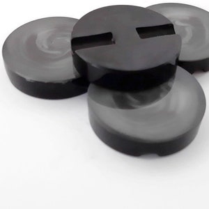May include: Four black coasters with a smooth, glossy finish. One coaster has a rectangular cutout in the center.