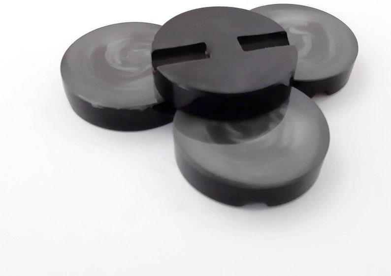 May include: Four black coasters with a smooth, glossy finish. One coaster has a rectangular cutout in the center.