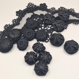 Peut inclure: Une collection de boutons noirs ronds présentant des motifs et des textures complexes en fil enroulé, disposés à côté d'un morceau de dentelle noire à bord festonné. Les boutons varient en taille et en design, mettant en valeur une broderie détaillée.