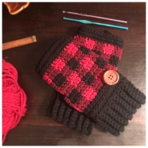 May include: Black and red crocheted fingerless gloves with a wooden button. The gloves have a plaid pattern.