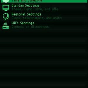 May include: A digital settings menu screen with a black background and bright green text and icons. The menu displays options for Clock Settings, Display Settings, Regional Settings, and WiFi Settings, with navigation buttons labeled BACK, SEL, UP, and DWN.
