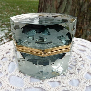 May include: A hexagonal glass box with a frosted floral design. The box has a gold-plated hinge and the inscription "G.S.E. ottone galvanizzato ORO".