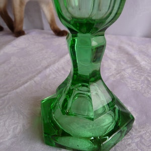 May include: A green glass goblet with a faceted base. The goblet is made of clear glass with a green tint.