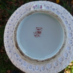 May include: The bottom of a white ceramic vase with a red Chinese character mark.