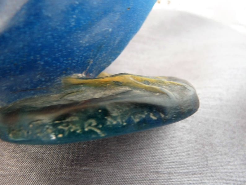 Pode incluir: Close-up da base de uma escultura de vidro azul com uma base amarela e verde. A escultura &eacute; assinada "R. Lalique".