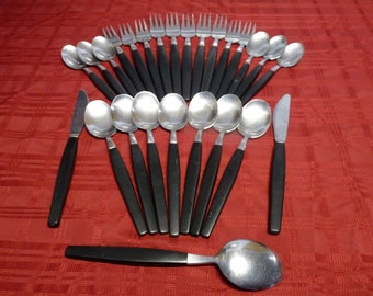 May include: A set of silverware with black handles. The set includes forks, spoons, and a knife. The silverware is arranged in a fan shape on a red tablecloth.