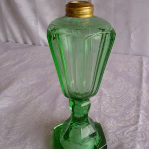 May include: A green glass oil lamp with a gold metal top and a faceted base.