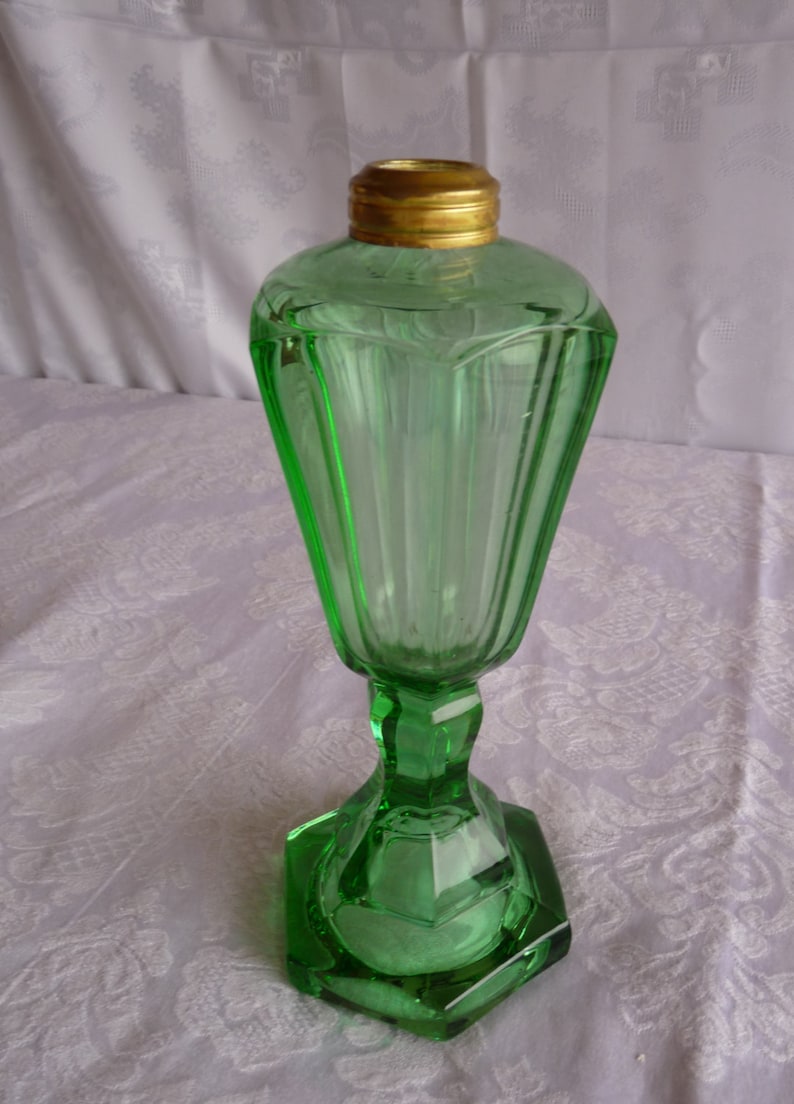 May include: A green glass oil lamp with a gold metal top and a faceted base.
