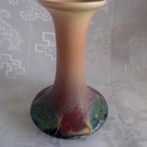 May include: A tall, slender ceramic vase with a flared base. The vase is decorated with a colorful abstract design in shades of red, green, and blue.