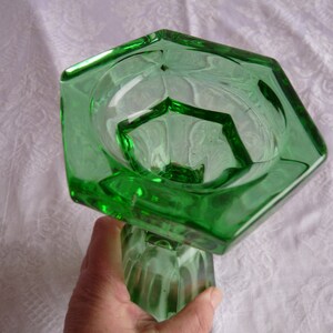 May include: A green glass vase with a hexagonal top and a fluted base.
