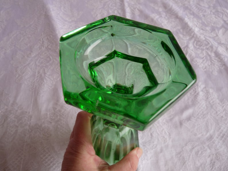 May include: A green glass vase with a hexagonal top and a fluted base.
