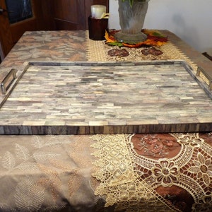 May include: Rectangular serving tray with a mosaic tile design in shades of gray, beige, and brown. The tray has metal handles and is suitable for serving food or displaying decorative items. The tray is approximately 20 inches long and 14 inches wide.