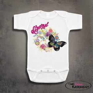 May include: White baby bodysuit with a colorful butterfly and floral design. The name "Cheryl" is written in pink script above the design. The butterfly has black wings with yellow, blue, and green accents.
