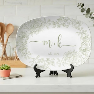 May include: White oval serving platter with a floral design in light green. The platter features the initials "m + k" and the year "est 2026" in a script font. The platter is displayed on a black stand.