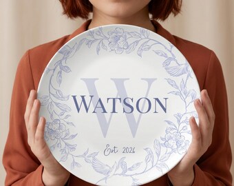 May include: White ceramic plate with a blue floral design and the name "WATSON" in a large, stylized font. The plate also features the text "Est 2026". The floral design includes flowers and birds.