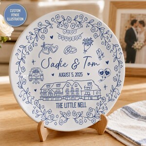 May include: A white ceramic decorative plate featuring blue line art illustrations of a wedding venue, a car, rings, and flowers. The text reads "JUST MARRIED", "Sadie & Tom", "AUGUST 5, 2025", and "THE LITTLE NELL" surrounded by a floral border.