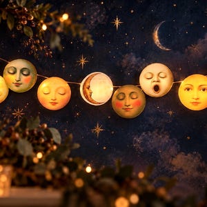 May include: A string of decorative lights featuring circular moon faces with various expressions, including closed eyes, sleeping faces, and an open-mouthed yawning face. The illuminated moon discs are connected by a thin wire against a dark blue background.