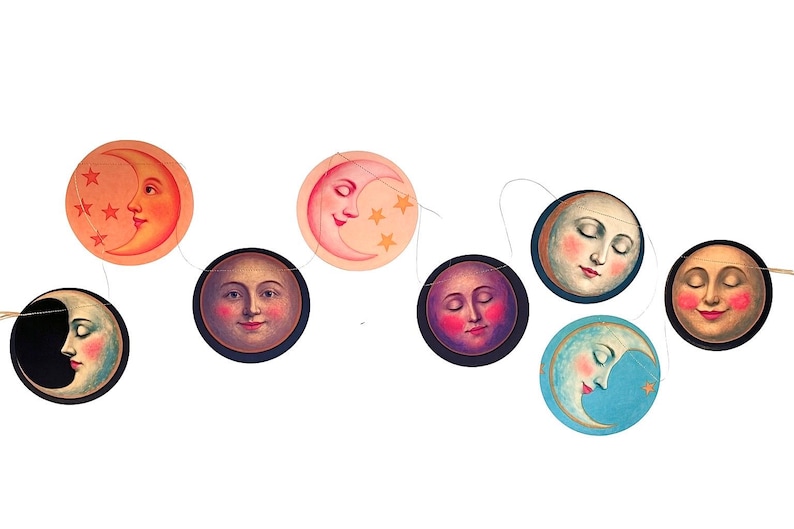 Op de afbeelding: Een decoratieve slinger bestaande uit zeven ronde papieren uitsneden opgehangen aan een dun touwtje. Elke uitsnede toont een unieke illustratie van een maan met een menselijk gezicht, uitgevoerd in kleuren zoals oranje, roze, blauw en donkerblauw.