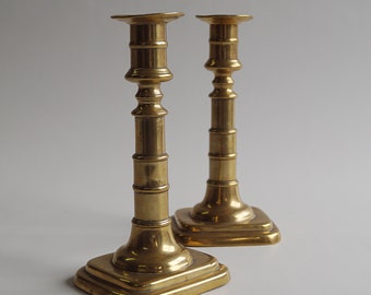 An elegant pair of English early Victorian brass candlesticks with pushers