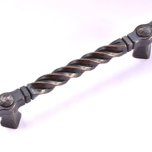 May include: A twisted, dark bronze cabinet pull with hammered metal accents. The pull is approximately 5 inches long.