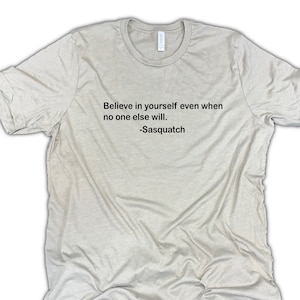 May include: A beige t-shirt with the text "Believe in yourself even when no one else will. -Sasquatch" printed on the front.