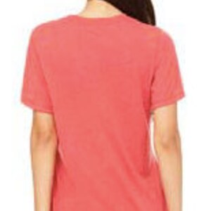 May include: A coral red short-sleeved t-shirt made of a soft, comfortable fabric. The shirt has a relaxed fit and a slightly distressed look.
