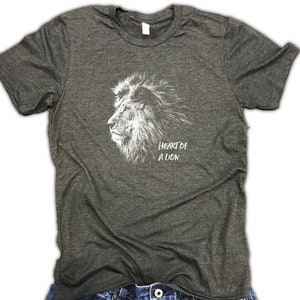 Puede incluir: Una camiseta gris oscuro jaspeada con un gr&aacute;fico blanco de una cabeza de le&oacute;n y el texto "Heart of a Lion".