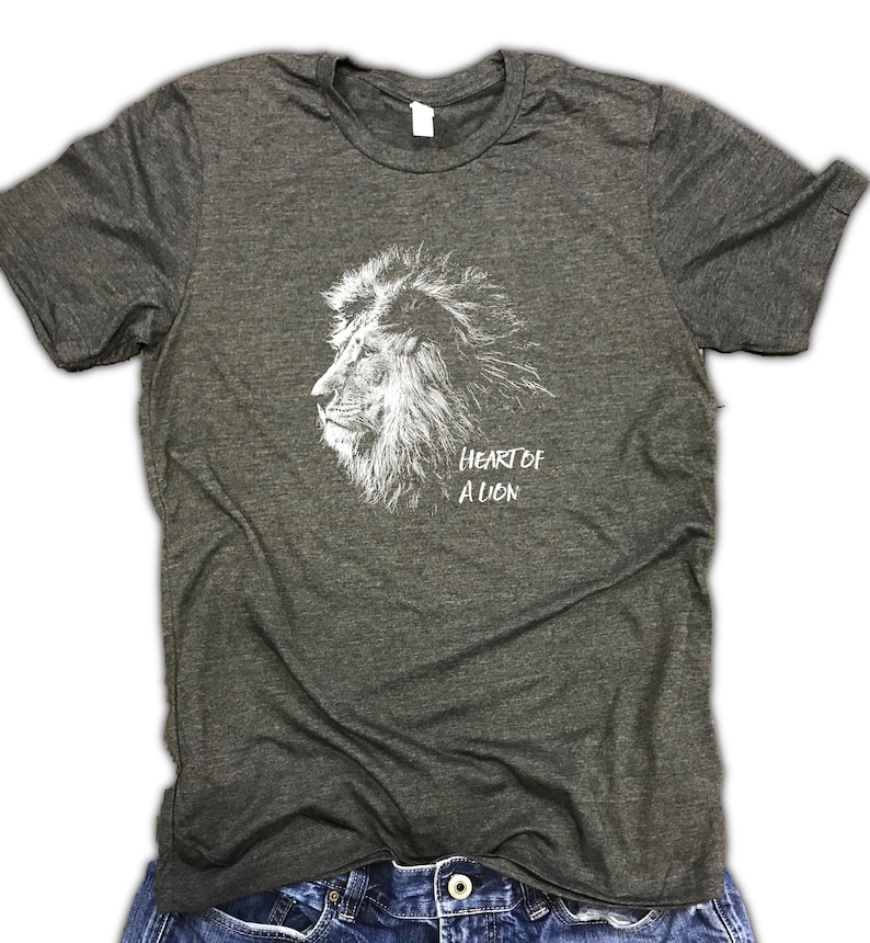 Puede incluir: Una camiseta gris oscuro jaspeada con un gr&aacute;fico blanco de una cabeza de le&oacute;n y el texto "Heart of a Lion".