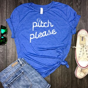 Pode incluir: Uma camiseta azul com um gr&aacute;fico branco que diz "pitch please" com um gr&aacute;fico de beisebol sobre o texto.