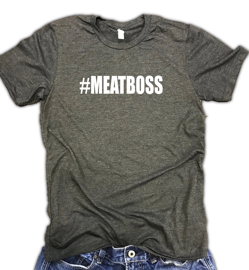 May include: A dark heather grey t-shirt with the text "#MEATBOSS" printed in white on the front.