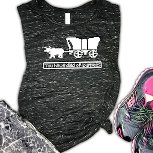 May include: A black and white tank top with a pixelated image of a covered wagon pulled by an ox. The text "You have died of burpees" is displayed below the image.
