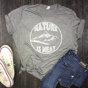 May include: Gray t-shirt with a white graphic of a mountain range and the text "Nature is Neat".
