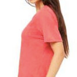 May include: A coral colored short-sleeved t-shirt made of a soft, comfortable fabric. The t-shirt is a relaxed fit and has a slightly distressed look.