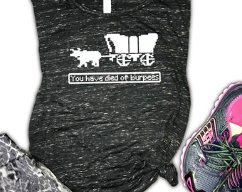 May include: A black and white tank top with a pixelated image of a covered wagon pulled by an ox. The text "You have died of burpees" is displayed below the image.