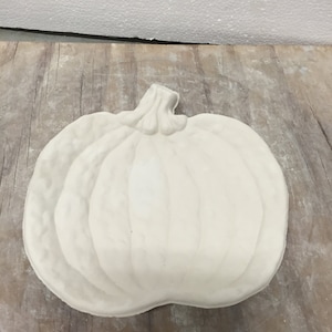 May include: White ceramic pumpkin shaped dish. The dish has a raised design of a pumpkin with a stem.
