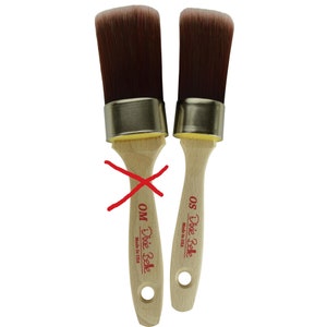 May include: Two Dixie Belle paint brushes with wooden handles and gold metal ferrules. The brush on the left is labeled "Dixie Belle OM Made in USA" and the brush on the right is labeled "Dixie Belle OS Made in USA".