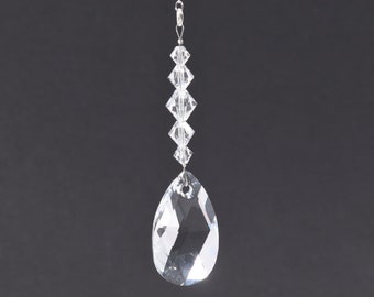 Op de afbeelding: Een heldere kristallen traanhanger met een zilveren ketting en een rij kleinere kristallen kralen.