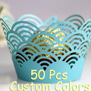 May include: Fifty blue cupcake wrappers with a scalloped design. The wrappers are made of paper and have a delicate, intricate pattern.  50 Pcs Custom Colors