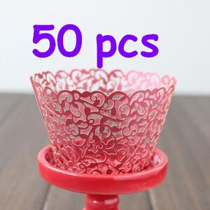 May include: 50 red cupcake liners with a delicate lace pattern. The liners are made of paper and are perfect for adding a touch of elegance to your cupcakes.
