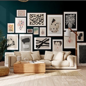 Op de afbeelding: Een woonkamer interieur met een witte bank en een houten salontafel. De muur is versierd met een galerijmuur van zwart-wit abstracte kunstprints, een print van een vrouw in een jurk en een print van een bloemstuk in een vaas. De muur is geverfd in een donker teal kleur.
