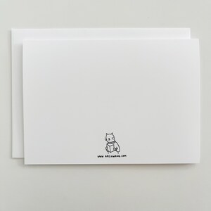 Puede incluir: Tarjeta blanca en blanco con una ilustraci&oacute;n en blanco y negro de un gato leyendo un libro. El texto "www.amyhwang.com" est&aacute; impreso debajo de la ilustraci&oacute;n.