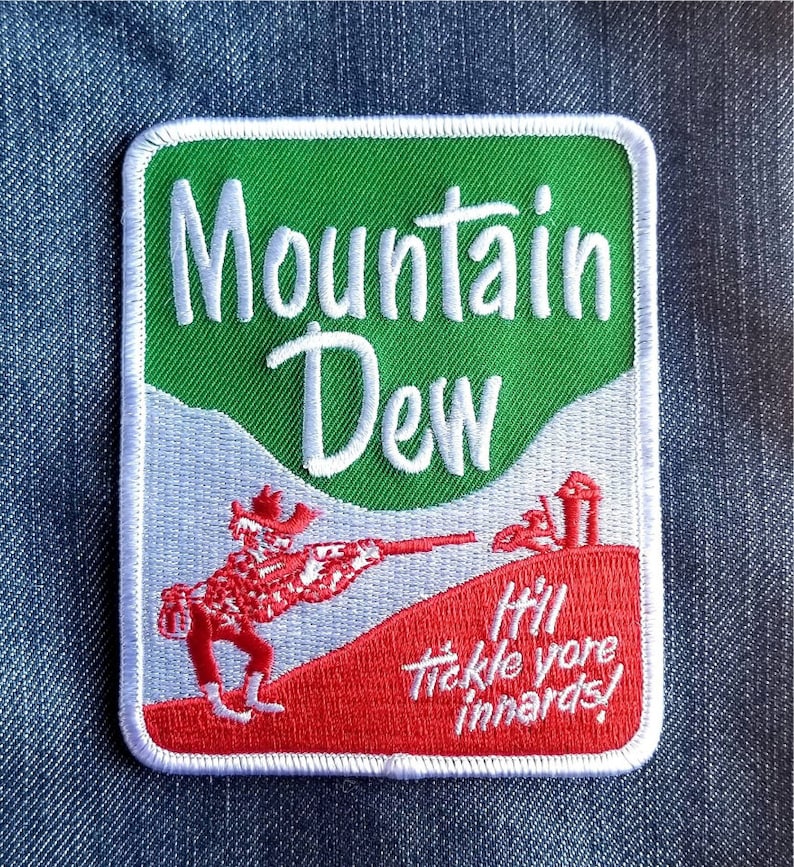May include: Embroidered patch with the Mountain Dew logo, green and white background, and a red figure aiming a rifle. The text reads "It'll tickle yore innards!"