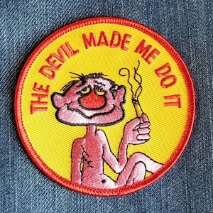 May include: A yellow and red embroidered patch with a cartoon character smoking a cigarette. The text on the patch reads "The Devil Made Me Do It."