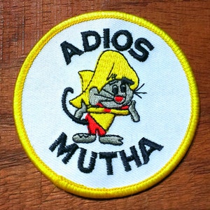 May include: Embroidered patch with a cartoon mouse wearing a yellow hat and red and yellow clothing. The patch has the words "ADIOS MUTHA" in black lettering on a white background, with a yellow border.