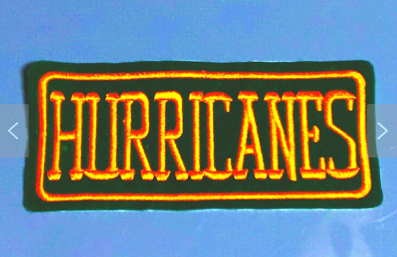 May include: A green embroidered patch with a yellow outline. The patch says "HURRICANES" in yellow lettering.