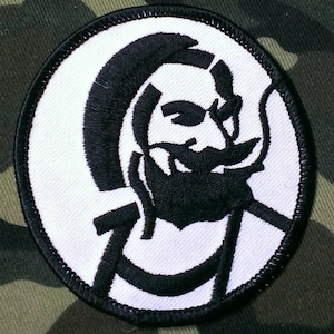 May include: A black and white embroidered patch with a stylized image of a person's head with a beard and a large letter C.