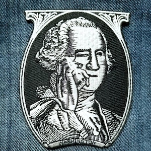 May include: Embroidered patch featuring a black and white portrait of George Washington within an oval frame. The patch has a decorative border and the name "WASHINGTON" is embroidered at the bottom. The patch is set against a blue denim background.