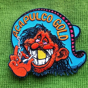 May include: A blue and orange embroidered patch with the text "ACAPULCO GOLD" and a cartoon character with a large grin and a cigarette in its hand.