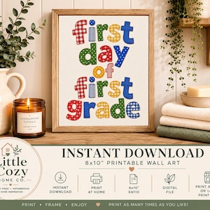 May include: A framed wall art print featuring the text "first day of first grade" in colorful, patterned, and polka-dot letters. The design uses red, blue, green, and yellow hues. The print is displayed in a light wood frame on a wooden surface.